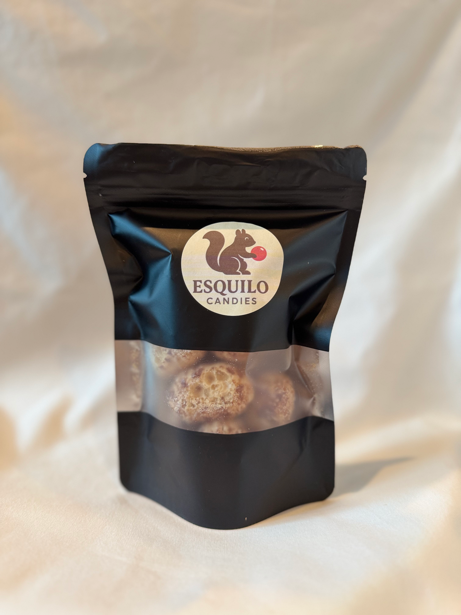 Black package of Esquilo Candies with freeze dried milk duds on a light background