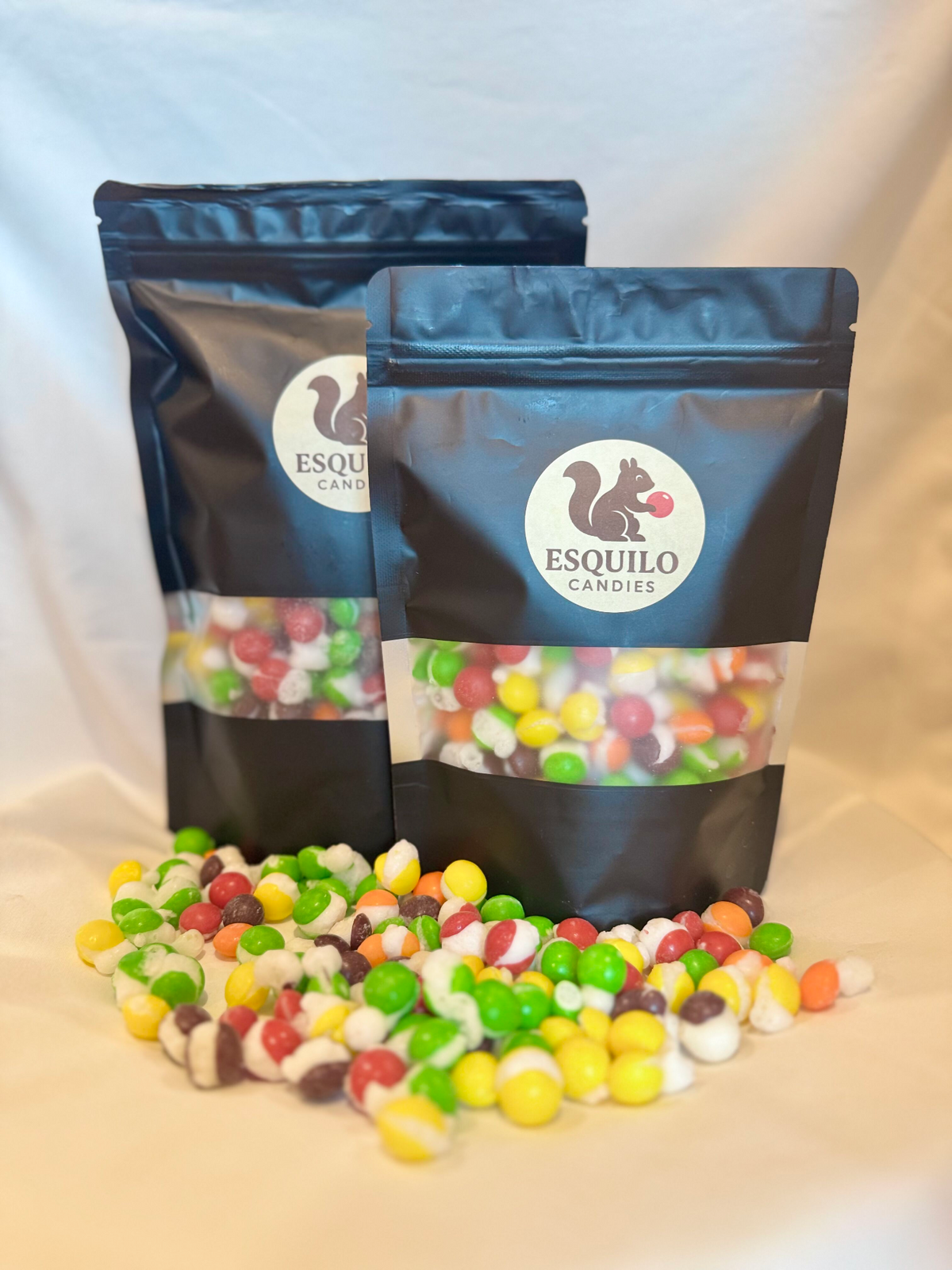 Two bags of Esquilo Candies with freeze-dried skittles spilling out on a light background